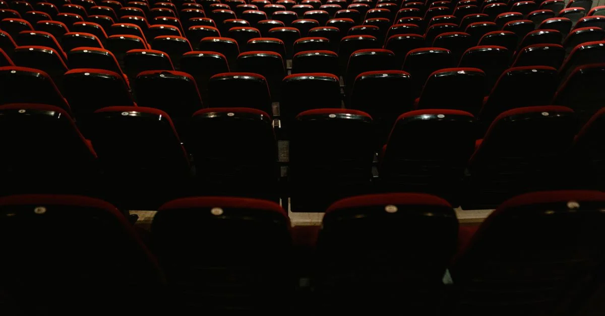 Un intérieur de cinéma vide avec des rangées de sièges rouges et noirs, attendant le public.