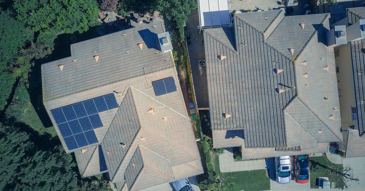 Vue de dessus des maisons avec panneaux solaires, mettant en avant l'énergie propre et la durabilité.